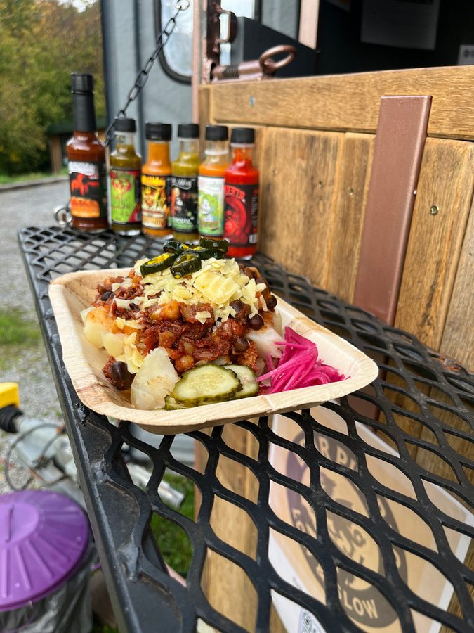 A loaded plate of BBQ with hot sauces on the table